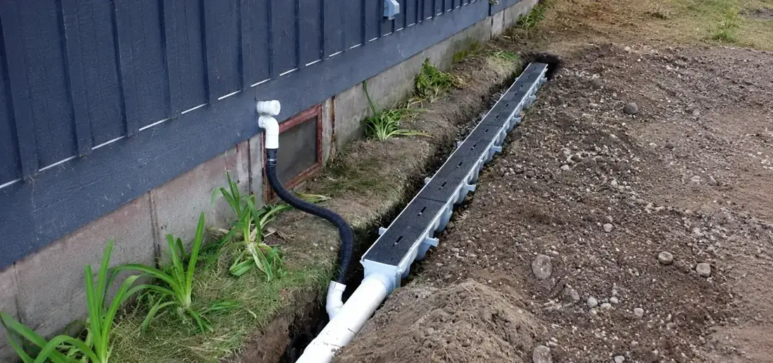 A channel drain being installed beside a building