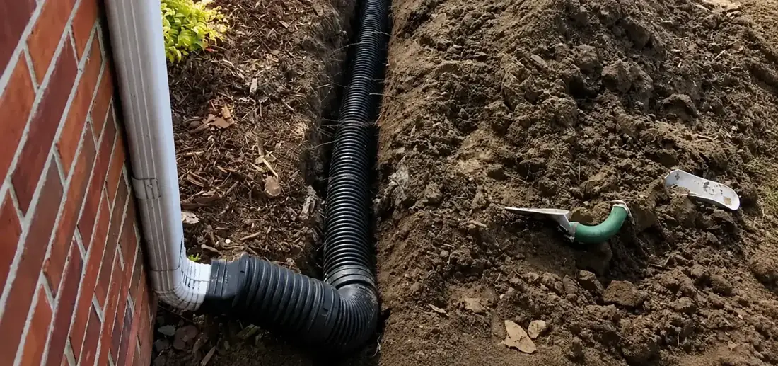 A corrugated land drain in a trench beside a building